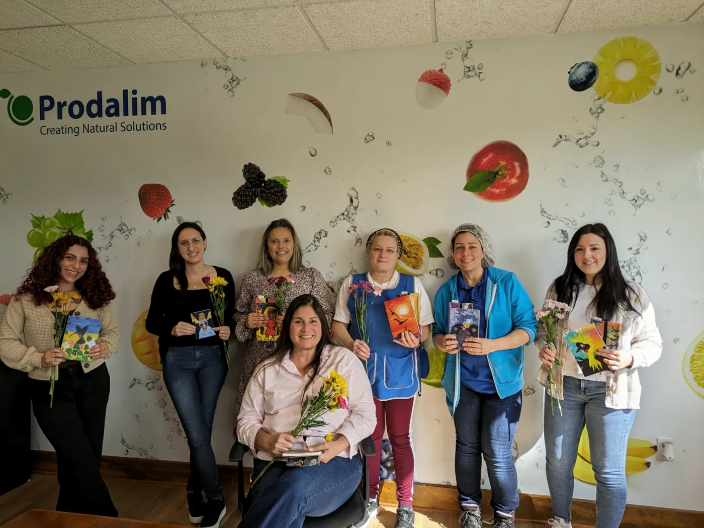 A company team holding notebooks and cards printed with children's artwork